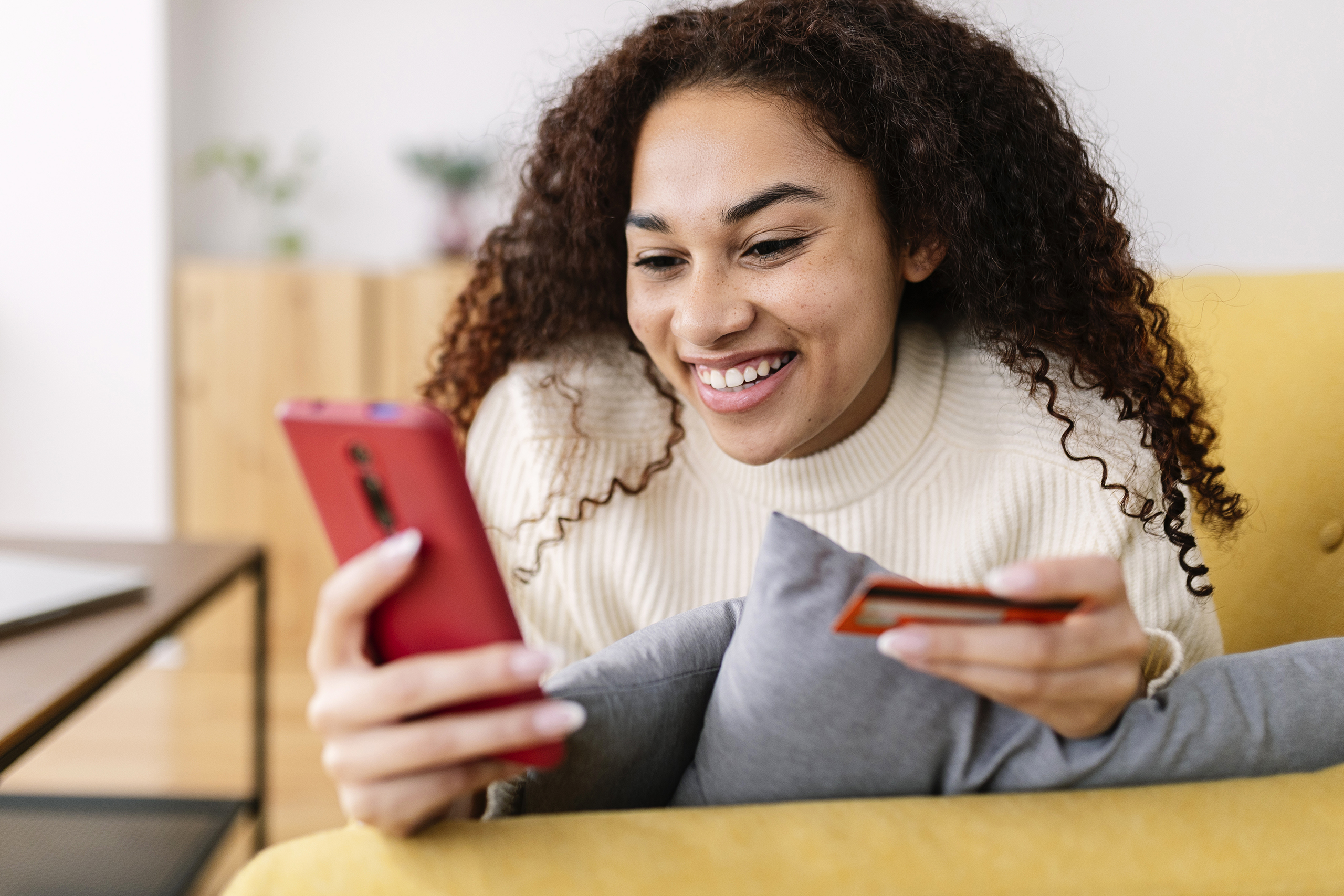 Young woman holding credit card and using mobile phone device to do shopping online in an e-commerce.